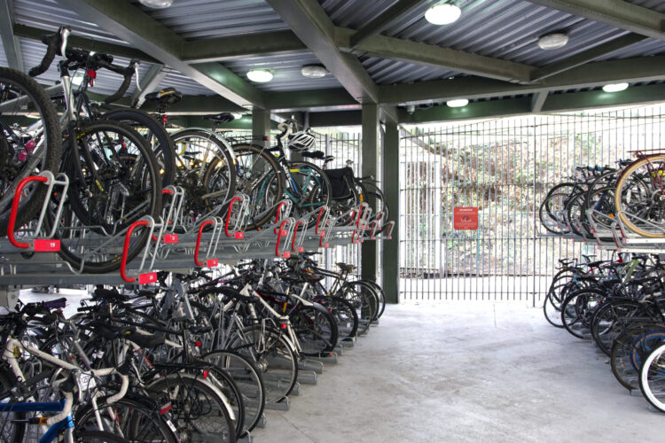 Bikes stored in rows of two-tiered metal bike racks underneath a metal canopy.