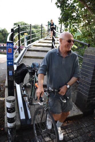 A man wheels his bike down a set of outdoor stairs using the adjoining bike ramp at Hackney, London.