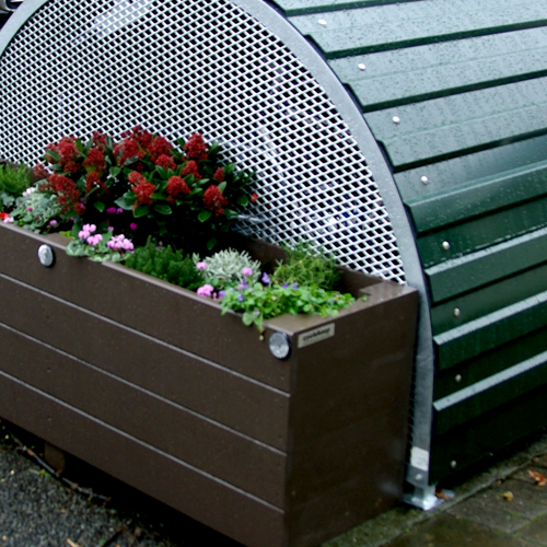A wooden planter against the perforated side wall of a dome-roofed Bikehangar bike storage container.