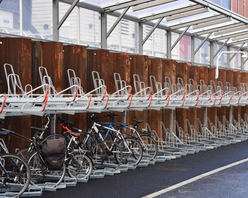 Bikes stored in a two-tier storage rack under a clear canopy.