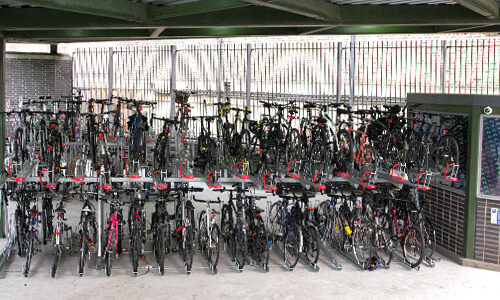 A two-tiered bike rack inside an undercover storage facility, packed with bicycles.