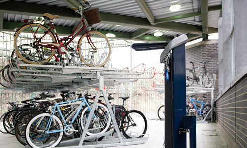An internal storage room for bikes, with double-layered metal bike racks and a Public Bike Repair Stand.