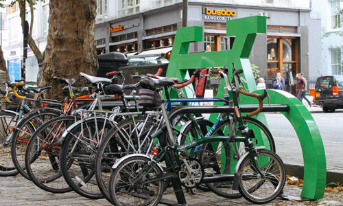 Bikes parked against a green Cyclehoop Bike Port in the shape of a large bicycle.