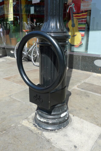 A matte black Cyclehoop bike stand affixed to a lamp post.