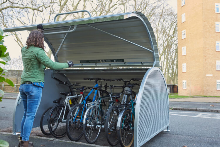 A person opens the curved door of a Cyclehoop Bikehangar with six bikes inside.