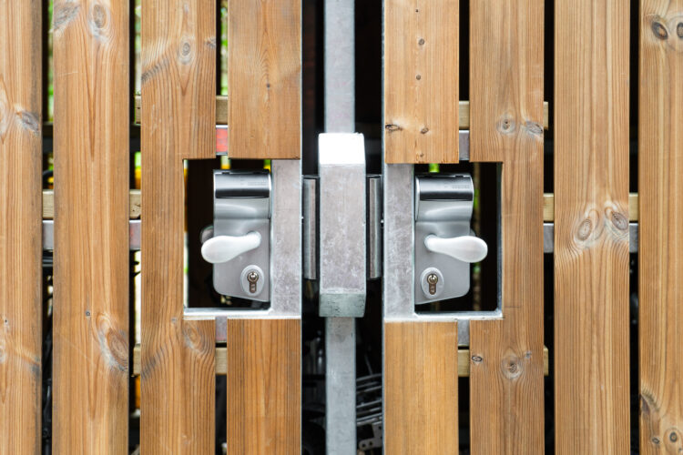 A close-up of the metal handle and lock system of a Wooden Bike Shelter, surrounded by wood panelling.