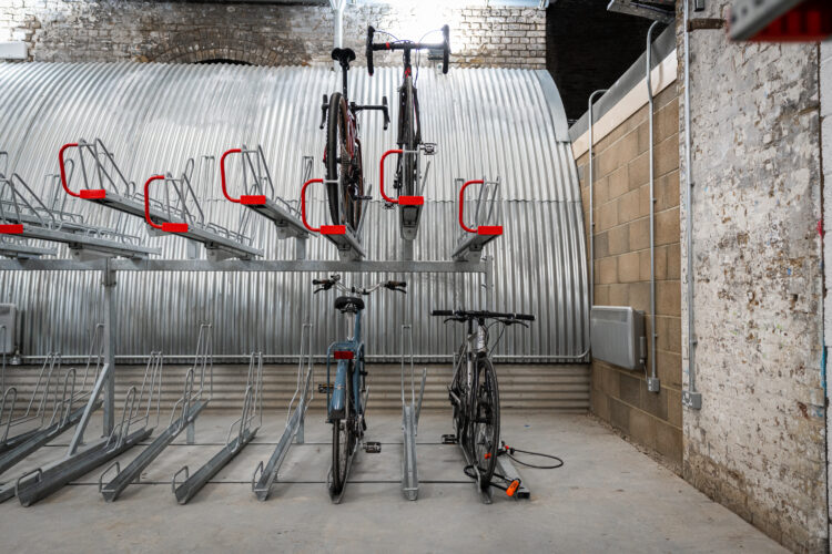 Bikes parked in a two-tier metal bike rack inside a storage room.