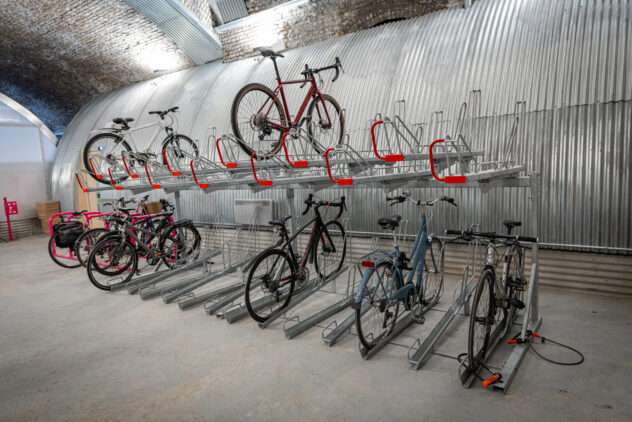 Bikes stacked on a double-layer bike storage rack inside a large room.