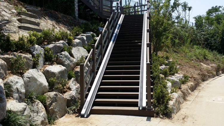 A staircase leading up an embankment on the side of a road, fitted with Bike Ramps on either side.
