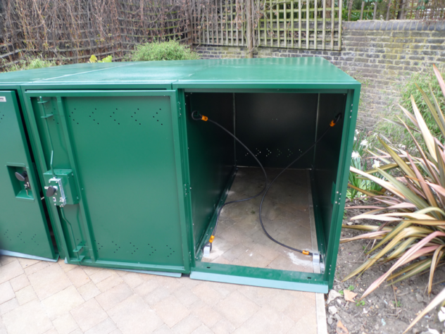 A green, metal, rectangular bike locker with one door open.