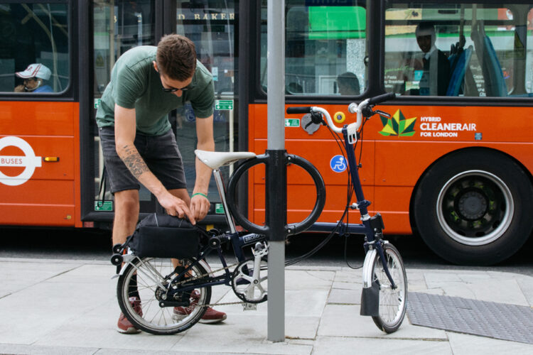 A man checking a bag on the rear of his bike, which is locked to a Cyclehoop HD