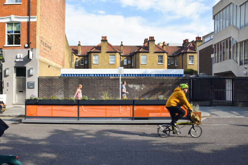 Man cycles past parklet on brompton