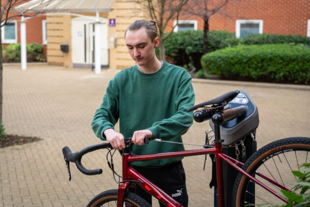 A man works on his bike, which is suspended from a public bike repair stand.