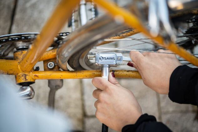 A person uses a metal tool on the wheel of a bike.