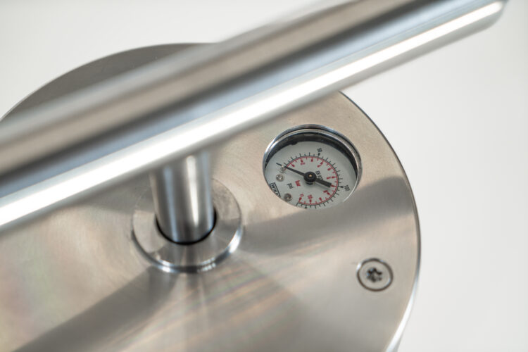 A close-up of a bike pump, showing a metal handle and a gauge.