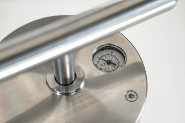 A close-up of a bike pump, showing a metal handle and a gauge.